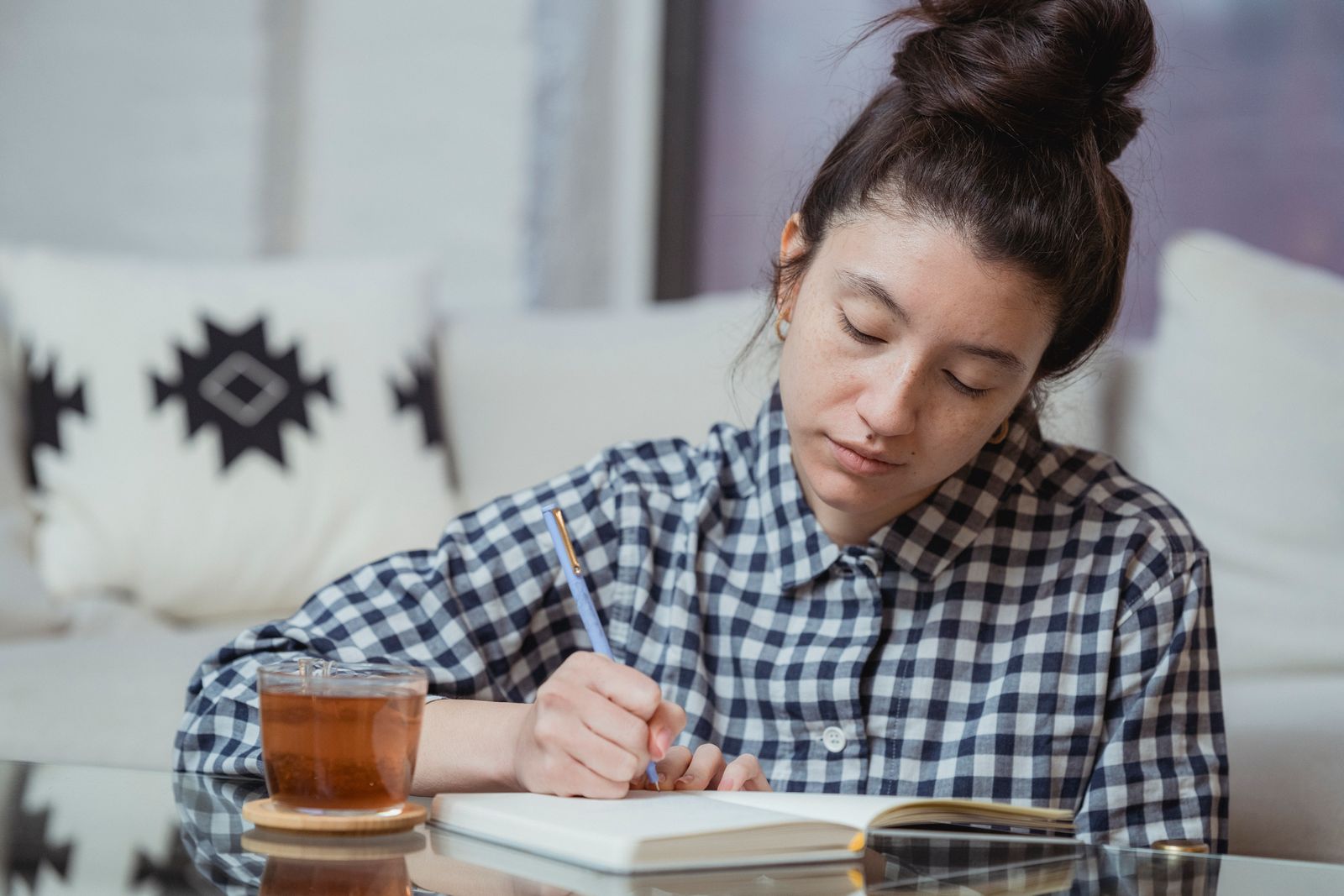 A woman writing notes in a notebook with a cup of tea